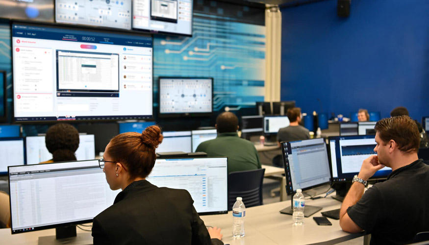 two cyberbit employees sitting at monitors and analyzing