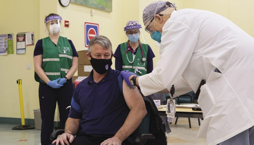 man wearing mask receiving Covid vaccine